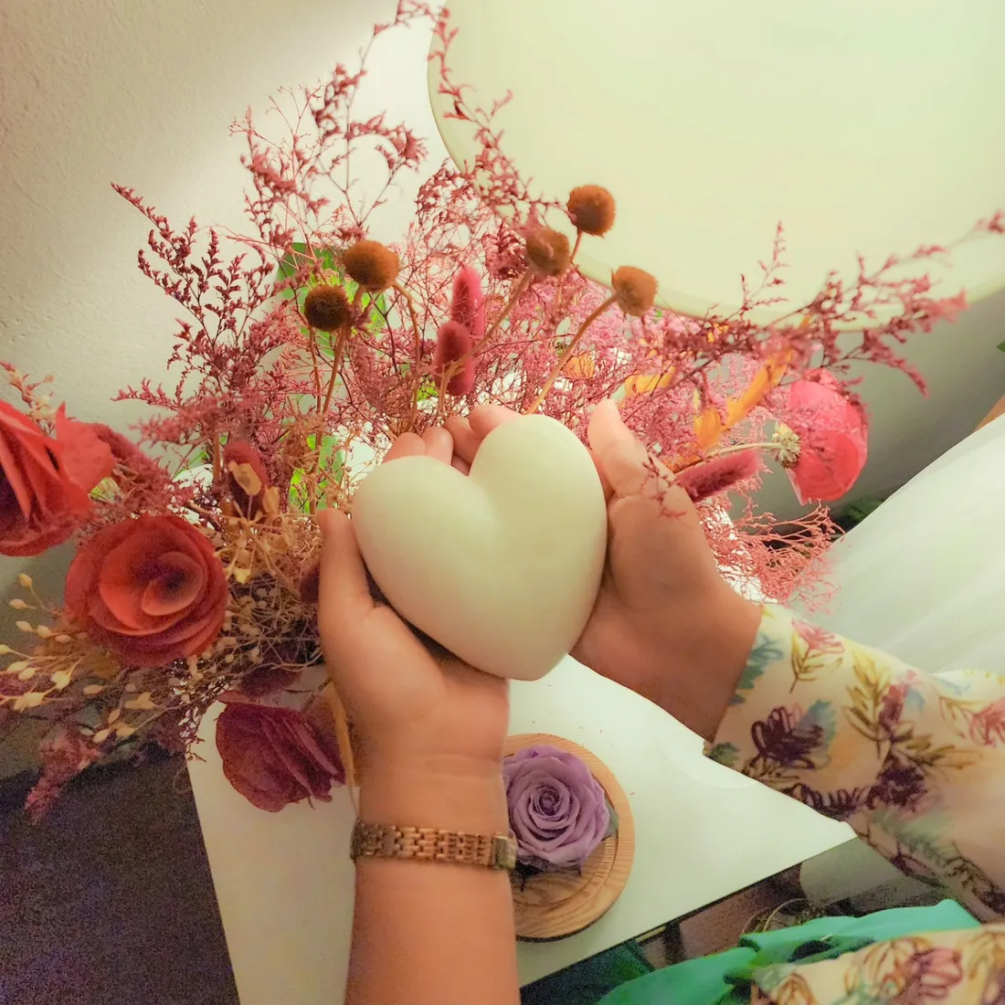 Manos sosteniendo un corazón entre flores